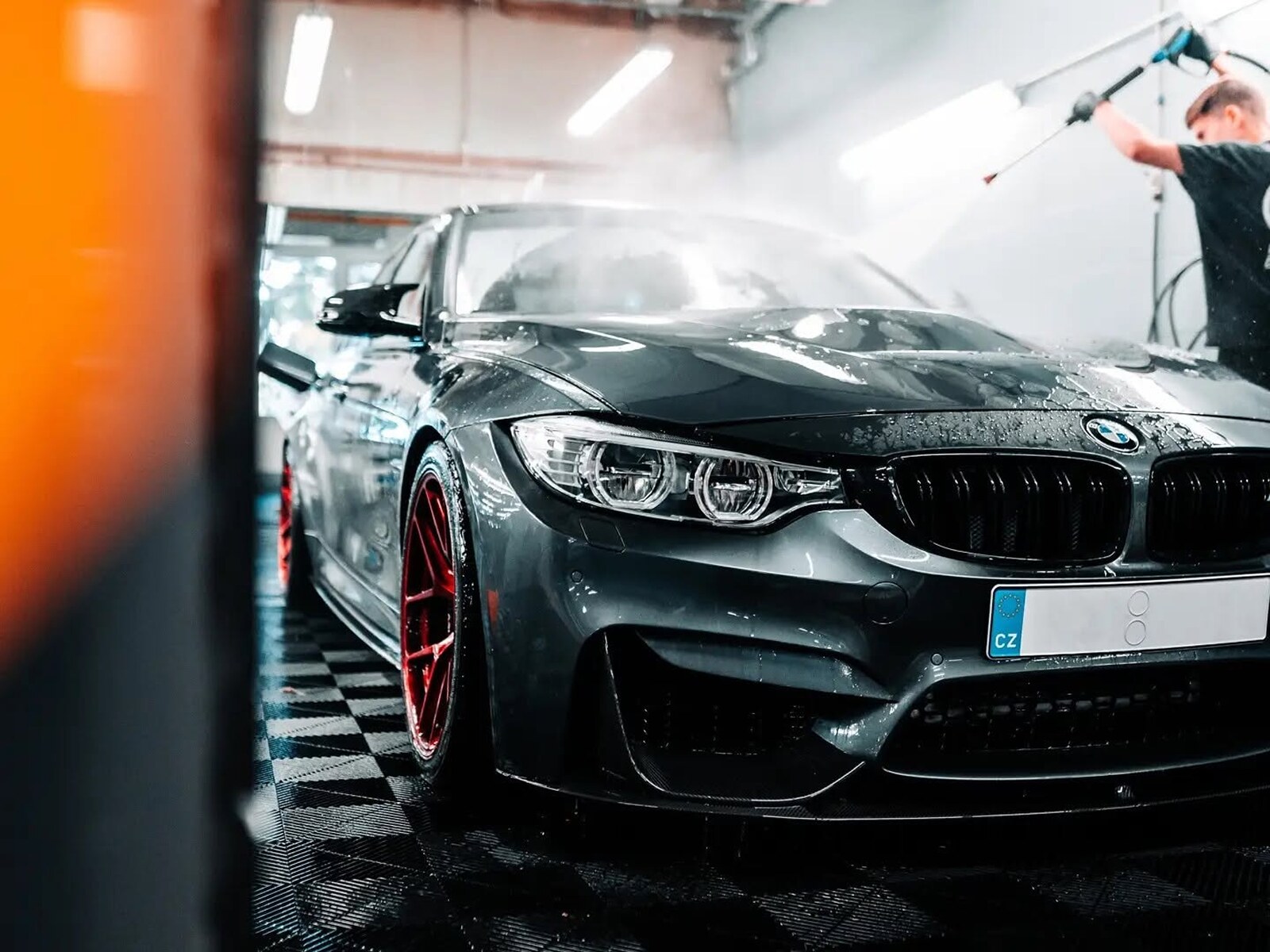 Ruční mytí šedého BMW M4 v detailingovém studiu