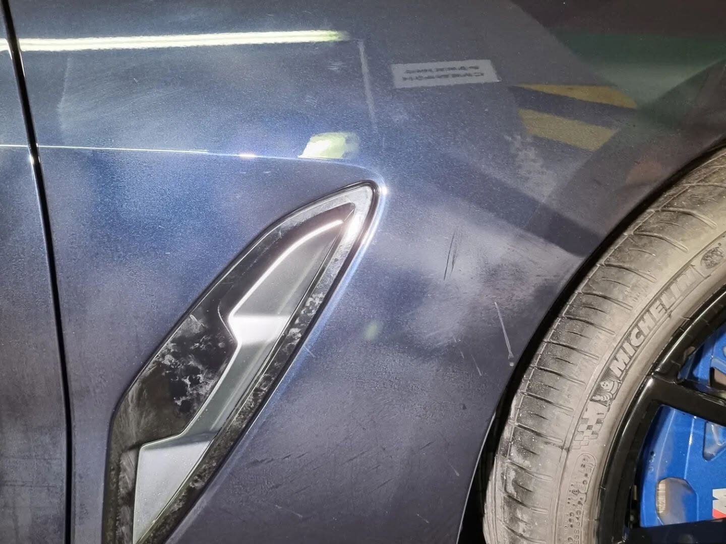 Matný lak u bočního průduchu modrého sportovního vozu před detailingem — Hommage Detailing